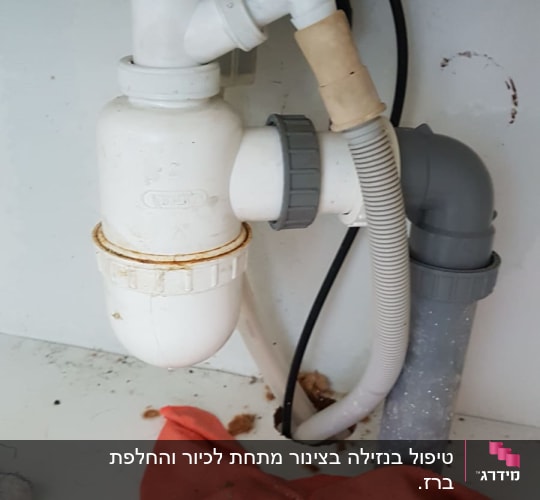 צנרת פלסטיק מתחת לכיור עם מגבת אדומה